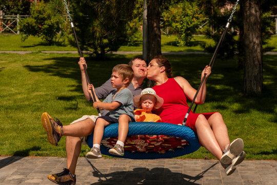 Mother Kissing Father During Family Playground Swing Ride