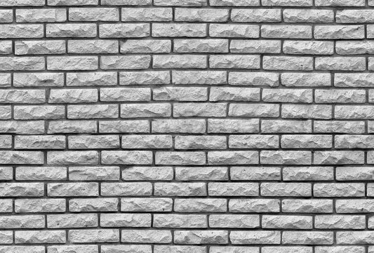 Neutral gray brick wall with rough stone texture and repeating pattern, ideal as a seamless background for architectural, construction, industrial, and graphic design