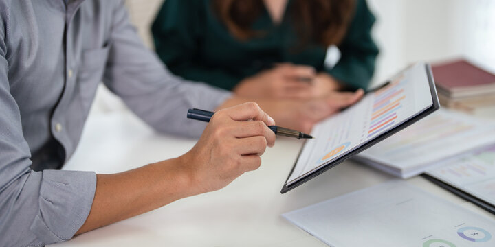 Close up hands of Two colleagues engaged in business analytics, over financial charts. Colleagues Collaborating on Business Analytics