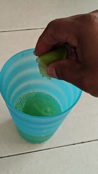 Squeezing Fresh Green Lime Piece into Green Beverage
