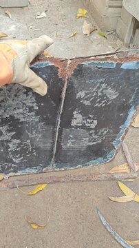 Gloved Hand Holding Old Rusted Sheet Metal