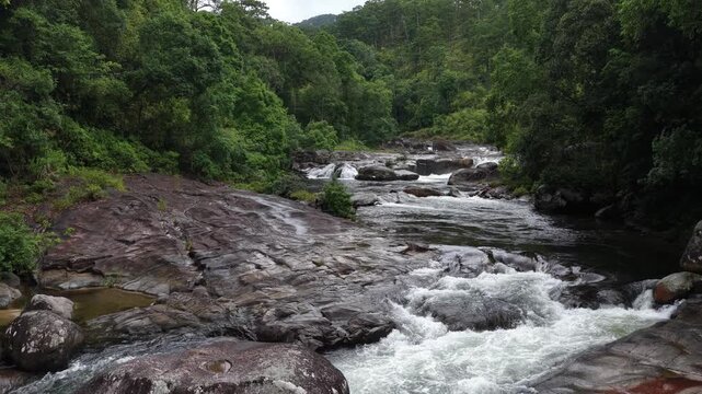 Low Aerial Drone Flight Up a Wild Forest Stream in Chu Yang Sin National Park, Dak Lak, Vietnam, Revealing Rocky Cascades Forming Multiple Small White Waterfalls