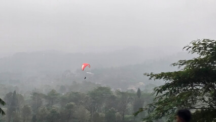 Paraglider Flying High in the Sky with Paraglider Wings Gliding Over Misty Landscape © Kaisar Kiandra