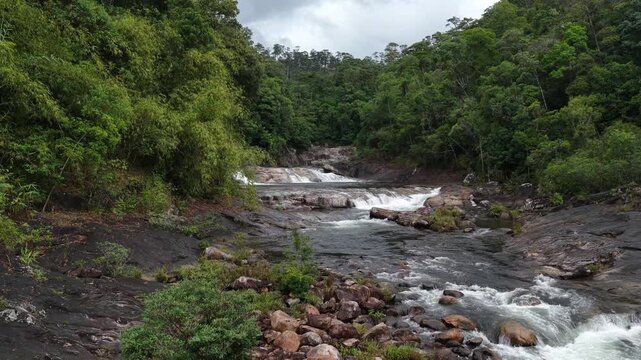 Low Aerial Drone Flight Along a Shallow Rocky Cascade in Chu Yang Sin National Park, Dak Lak, Vietnam, Showing a Wide Stretch of Gently Flowing Water Over Uneven Rocks Deep in the Forest
