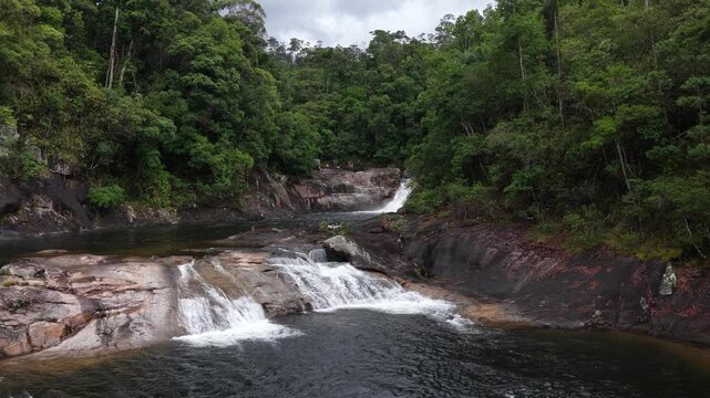 Low Aerial Drone View of a Wild Mountain Stream and Wide Waterfall in Chu Yang Sin National Park, Dak Lak, Vietnam, Cascading into a Small Natural Pool Surrounded by Dense Forest