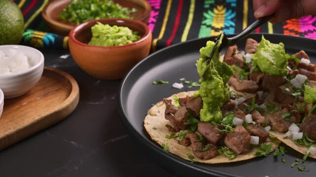 Dropping guacamole on delicious carne asada tacos