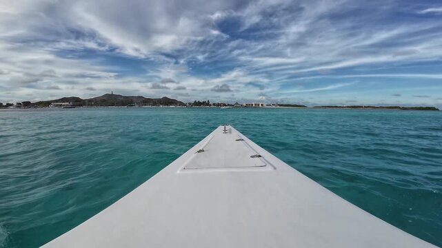 Bow view sailing through crystal-clear turquoise Caribbean waters towards Gran Roque, Los Roques Archipelago, Venezuela