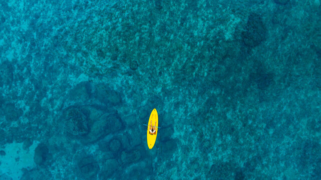Aerial view of a woman and a young man kayaking on clear blue waters at Andaman Island. She does water sports activities	
