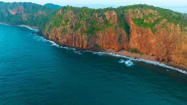 Aerial view of a dramatic, rugged rocky cliff coastline meeting the deep blue ocean water, representing natural beauty, adventure, and travel destinations.concept nature