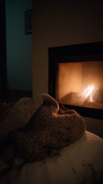 Knitted throw blanket draped over a bed near a cozy fireplace.