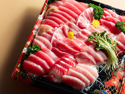 Premium assorted tuna sashimi platter including otoro and chutoro in a takeout bento box, white background with copy space