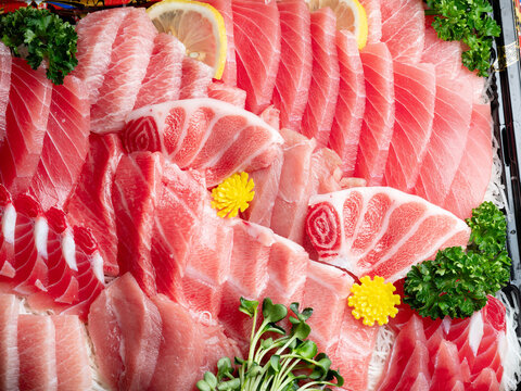 Premium assorted tuna sashimi platter including otoro and chutoro in a takeout bento box, white background with copy space