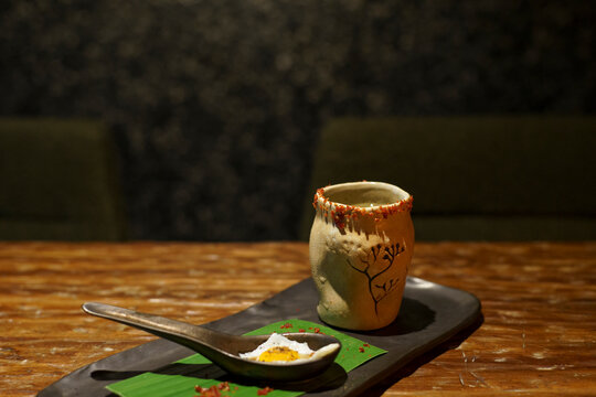A glass of a unique cocktail "Kaprao Moo Krob Kai Dao Mai Sook (crispy pork with chili  basil and fried egg)" which is based on Thailand's food of the same name inside a bar in Bangkok, Thailand