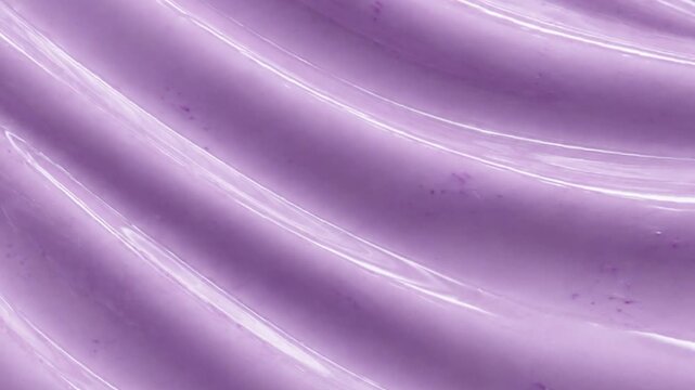Abstract background pattern of smooth creamy purple taro paste with soft wavy ridges. Macro close up of glossy purple lavender cosmetic cream or blueberry yogurt texture with video play button.