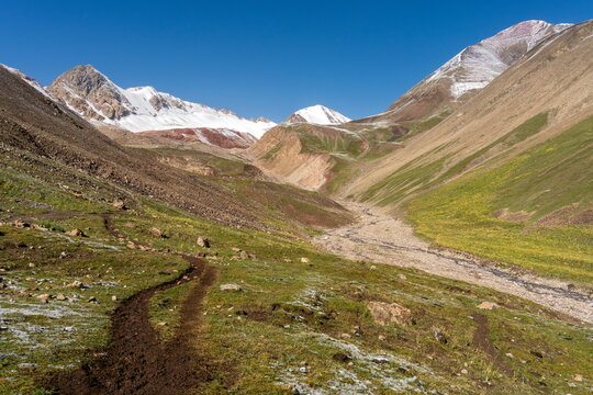 Fresh snow on peaks above Razvedyvatelny stream near trail to Travelers Pass, Pamir in Summer