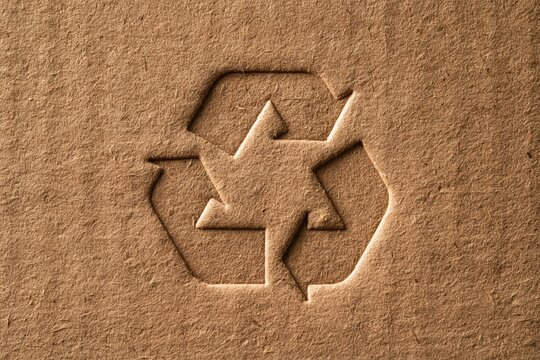Recycle symbol embossed on a brown cardboard texture