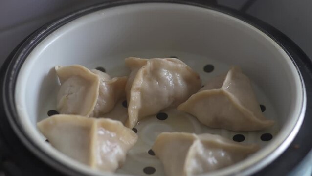 Freshly steamed Chinese dim sum dumplings inside a white steamer.