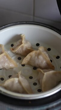 Freshly steamed Chinese dim sum dumplings inside a white steamer.