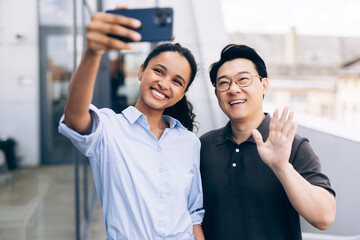 Obraz premium Diverse colleagues smiling and waving while taking selfie