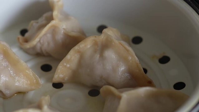 Freshly steamed Chinese dim sum dumplings inside a white steamer.