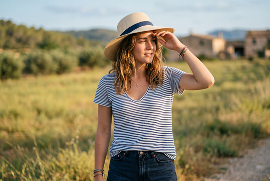 Young woman wearing striped shirt and hat in rural landscape