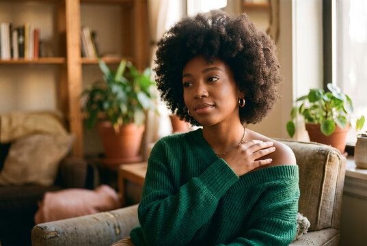 African American young woman sitting on couch in modern home interior