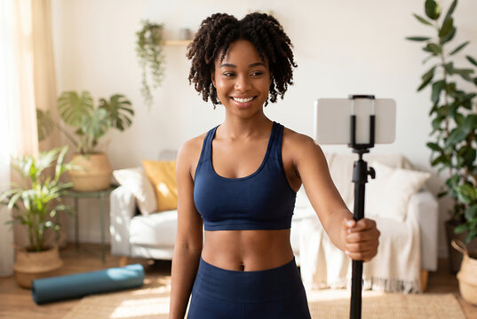 Young African American woman filming fitness content at home