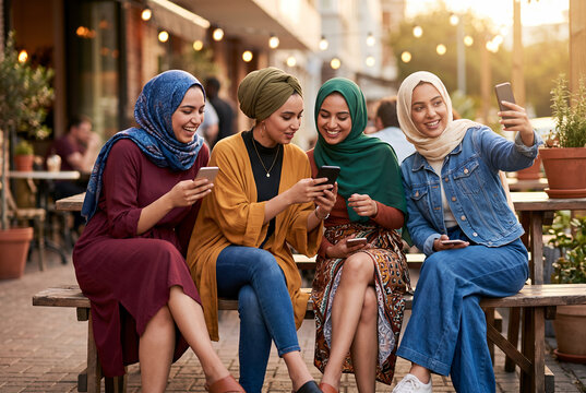 Diverse young women friends taking selfie outdoors at cafe