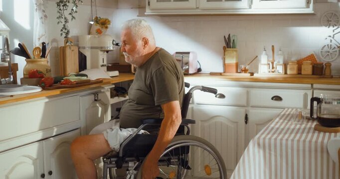 Senior man in a wheelchair independently prepares breakfast in his kitchen, showing an active and positive morning routine at home.