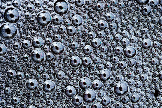 Close-up of symmetrical black beer foam bubble texture background