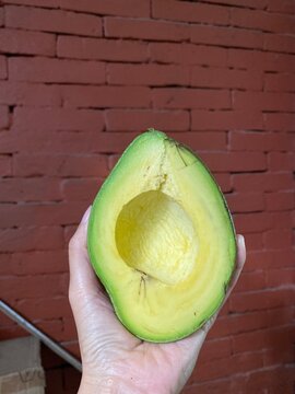 a hand is bringing a half of avocado