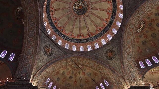 Interior view of the ornate walls and ceilings decorated with tiles and painted floral inside the historic mosque in Istanbul.