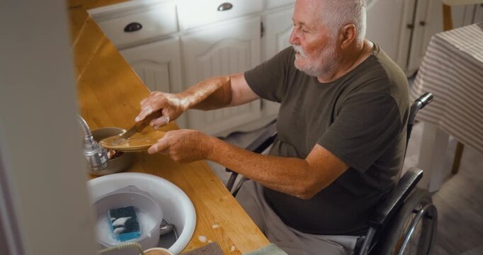 Senior man in a wheelchair washes dishes at the kitchen sink after breakfast, showing independent daily life and active living at home.
