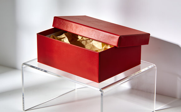 A red gift box with its lid open, placed on a transparent stand