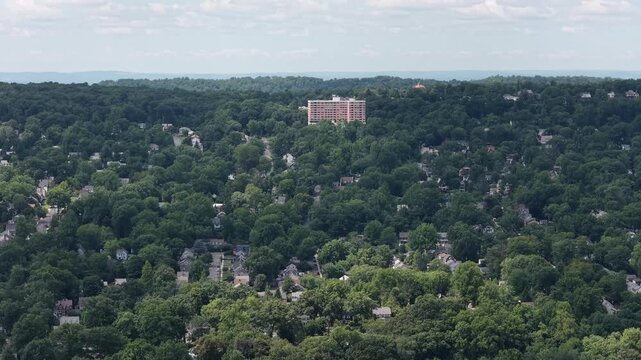 A controlled lateral pan surveys dense forest canopy, hillside homes and a distant apartment building near South Mountain, Maplewood and South Orange.