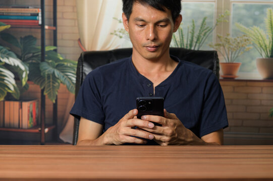 Young Man Using Smartphone in Modern Indoor Workspace Setting