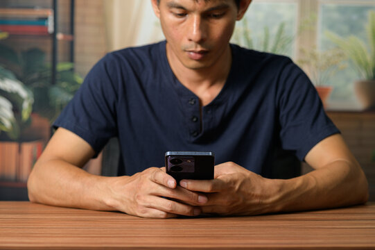 Young Man Engaged with Smartphone in Cozy Indoor Setting