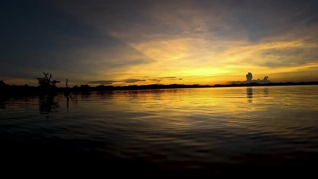 Dramatic Orange Sunset Over Amazon River in Ecuador with Dark Tree Silhouettes, Calm Water Reflections and Remote Tropical Wilderness Scene