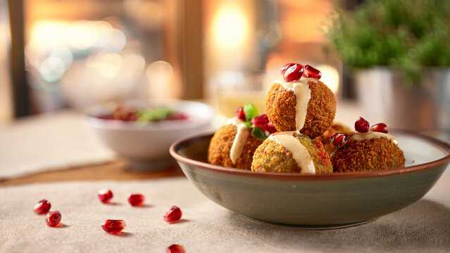 Crispy falafel bowl with tahini drizzle and blurred restaurant background banner.