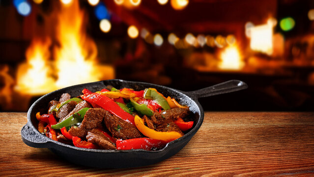 Sizzling beef fajitas in cast iron skillet with blurred cantina background banner.