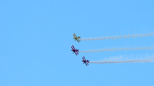 Three Vintage Biplanes Flying in Formation with Smoke Trails