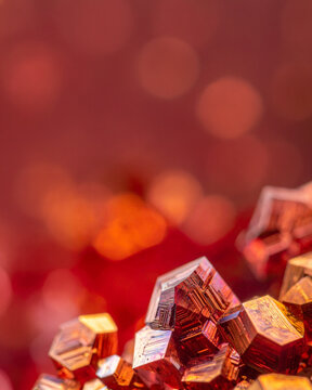 Bismuth metal crystal structure macro photograph. Copper gold geometry blocks over red bokeh background. Commercial templates for science technology industry geology network pattern presentation sets.