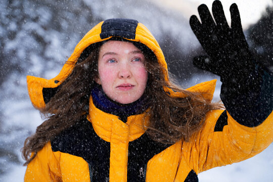 Female mountaineer making her way through strong wind and snowfall during a winter ascent in the mountains. Front view portrait.