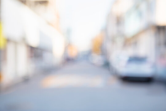 Abstract blurred urban local neighborhood street background with white buildings and a parked car