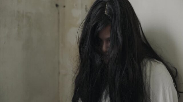 Scary halloween devil ghost with black long disheveled hair and white costume portrays a psychopath dead on day or night creating eerie unsettling suspenseful haunted atmosphere perfect for horror.