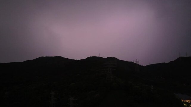 Silhouette of mountains and power transmission towers in the dark night sky