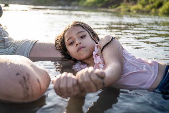 Young girl resting beside her mother in a river