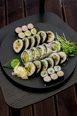 Assorted sushi rolls beautifully arranged on a black platter © Cavan