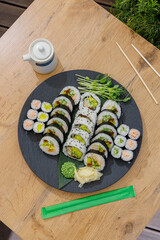 A large platter of assorted sushi rolls on a wooden table © Cavan