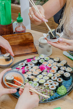 Friends sharing a large platter of assorted sushi rolls